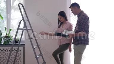 家庭装修，美丽的情人挂画和架子在白色的墙上使用梯子在公寓